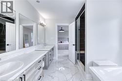 Bathroom featuring a dual vanity with light-toned wood-finish cabinetry and white countertops, a walk-in shower with dark subway tile surround, a built-in shower bench, and white marble-look floor til - 