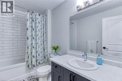 Bathroom featuring a white subway tile shower surround, a built-in tub, a dark wood-finish vanity with an integrated sink and light countertop, and patterned floor tile - 