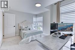 Bedroom featuring wall-to-wall carpeting, white interior door with black hardware, and an upholstered headboard - 