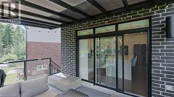 Covered outdoor patio with dark brick exterior and a clear glass railing - 