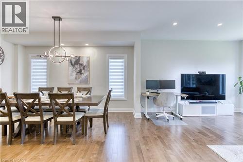 Open-concept interior featuring wood-finish flooring, recessed lighting, and a modern linear chandelier - 71 Ian Ormston Drive, Waterloo, ON 