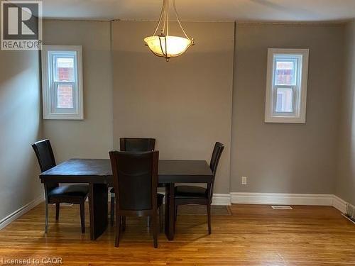 Hardwood flooring throughout featuring two windows with white trim and a central ceiling light fixture - 1066 Richmond Street, London, ON 