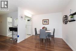 Open-concept living space featuring wood-finish flooring, white walls, and bright overhead lighting - 
