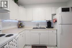 White kitchen featuring shaker-style cabinetry, a subway tile backsplash, and light-toned countertops - 