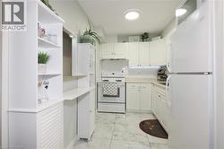 Bright kitchen featuring white cabinetry, white appliances, white subway tile backsplash, light-toned countertops, and wood-finish accent shelving - 