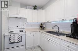 White kitchen featuring white cabinetry, light countertops, a dual basin sink with a chrome faucet, and a white subway tile backsplash - 