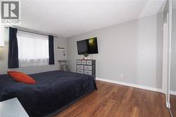 Spacious room featuring wood-finish flooring, a large window with privacy sheers, and light gray painted walls - 
