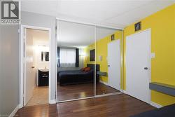 Room featuring wood-finish flooring, a full wall of mirrored closet doors, and direct access to a bathroom - 