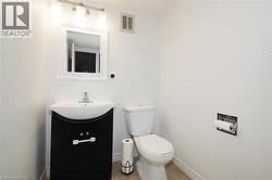 Bathroom vanity with a white framed mirror and three-light fixture above, featuring a white basin sink, chrome faucet, and a black base cabinet - 
