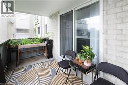 Covered balcony featuring brick veneer siding, a sliding glass door, and a patterned area rug - 