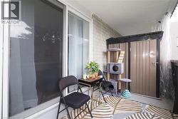 Outdoor balcony with white brick wall, sliding glass door, and dedicated storage unit - 