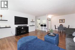 Living area featuring wood-finish flooring and a built-in electric fireplace console - 