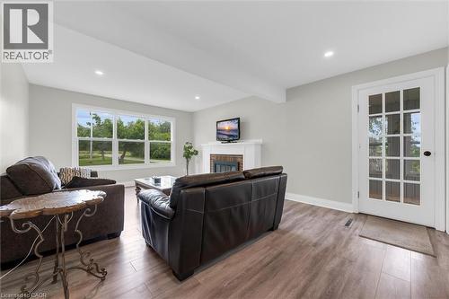 Bright living area featuring wood-finish flooring, a white mantel fireplace, and recessed lighting - 87 Mud Street E, Grimsby, ON 