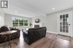 Bright living area featuring wood-finish flooring, a white mantel fireplace, and recessed lighting - 