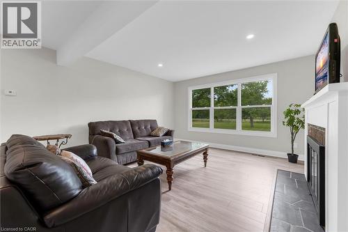 Spacious living area featuring light wood-finish flooring, recessed ceiling lighting, and a large multi-pane window - 87 Mud Street E, Grimsby, ON 
