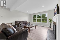 Spacious living area featuring light wood-finish flooring, recessed ceiling lighting, and a large multi-pane window - 