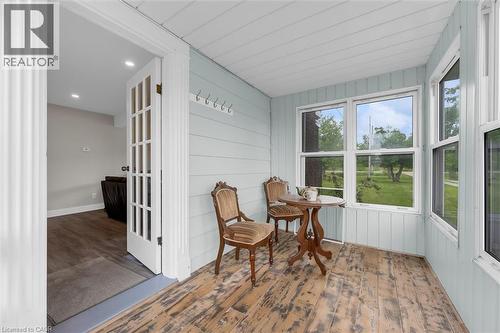 Enclosed porch featuring light blue paneled walls, white trim, and distressed wood-finish flooring - 87 Mud Street E, Grimsby, ON 