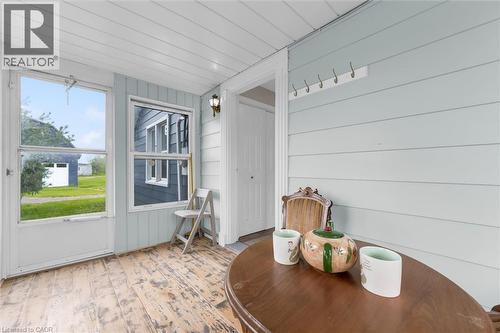Enclosed porch featuring wood-finish flooring, light blue paneled walls, and a white plank ceiling - 87 Mud Street E, Grimsby, ON 