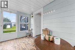 Enclosed porch featuring wood-finish flooring, light blue paneled walls, and a white plank ceiling - 