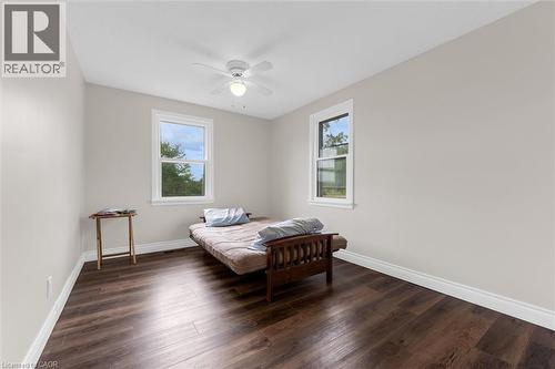 Bright room featuring dark wood-finish flooring, light neutral wall paint, and crisp white baseboards - 87 Mud Street E, Grimsby, ON 