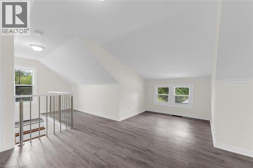 Spacious loft area featuring wood-finish flooring, abundant natural light from multiple windows, a modern metal railing, sloped ceilings, and recessed lighting - 87 Mud Street E, Grimsby, ON 