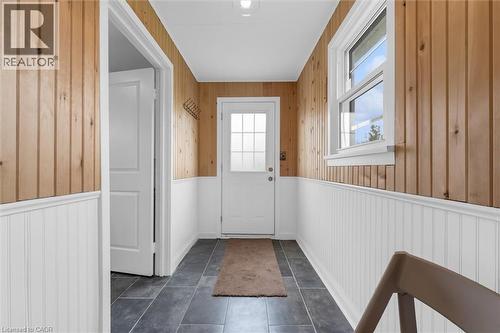 Entryway featuring wood plank walls, white beadboard wainscoting, and large format dark tile flooring - 87 Mud Street E, Grimsby, ON 