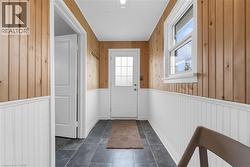 Entryway featuring wood plank walls, white beadboard wainscoting, and large format dark tile flooring - 