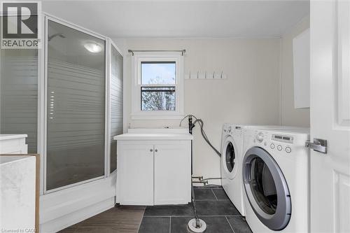 Shower enclosure with frosted glass panels, white cabinetry, a utility sink, and durable tile flooring - 87 Mud Street E, Grimsby, ON 