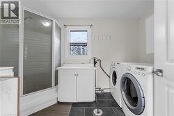 Shower enclosure with frosted glass panels, white cabinetry, a utility sink, and durable tile flooring - 