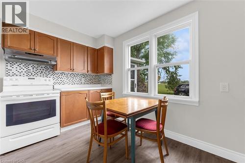 Kitchen features wood-finish cabinetry, a mosaic tile backsplash, and a white electric range with an overhead vent - 87 Mud Street E, Grimsby, ON 