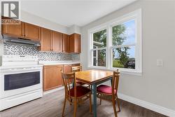 Kitchen features wood-finish cabinetry, a mosaic tile backsplash, and a white electric range with an overhead vent - 