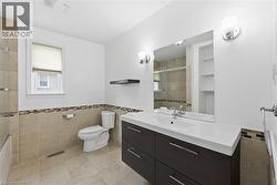 Full bath featuring vanity, tile walls, a wainscoted wall, light tile patterned flooring, and shower / bath combination with glass door - 