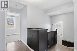 Hall with light wood-style flooring and an upstairs landing - 