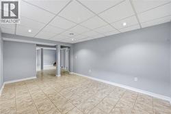 Finished basement with a paneled ceiling, recessed lighting, and light tile patterned flooring - 