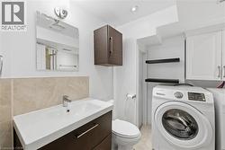 Half bath with vanity, washer and dryer, light tile patterned floors, and backsplash - 