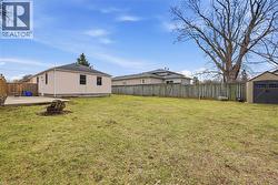 Fenced backyard featuring a storage unit, an outdoor fire pit, and a patio area - 