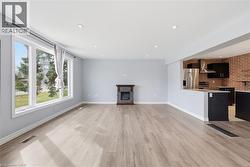 Unfurnished living room featuring brick wall, a fireplace, light wood-type flooring, and recessed lighting - 