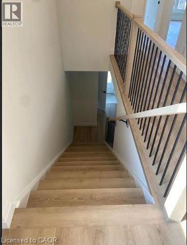 Staircase with wood-finish treads and risers, white baseboards, and a contemporary railing system featuring a light wood-finish handrail and black metal balusters - 48 Melbourne Street, Hamilton, ON - Indoor Photo Showing Other Room
