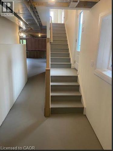 Staircase with painted treads and risers, featuring a wood newel post and a partial glass door - 48 Melbourne Street, Hamilton, ON - Indoor Photo Showing Basement