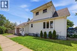 White siding exterior with an attached garage, featuring a shingled roof, front entry door, and multiple windows - 