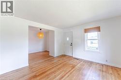 Living Room opening to dining area featuring original hardwood flooring, front door, and a central window. - 