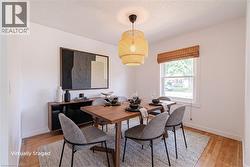 Dining area featuring original hardwood flooring and a central window with a woven shade - 