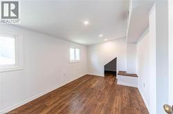 Spacious bedroom featuring two windows, wood-finished flooring, recessed lighting, and a built-in window bench with additional storage room - 