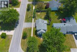 Property featuring a residential structure with a gray shingle roof, a paved driveway, and established trees - 