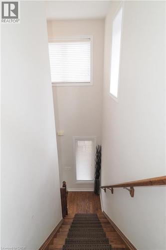 Stairwell featuring a carpeted staircase with wood-finish treads, a wood handrail, and high ceilings - 213 Seabrook Drive, Kitchener, ON 