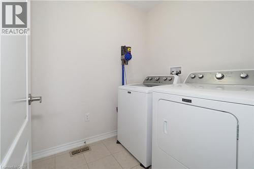 Laundry area featuring neutral wall paint, tile flooring, and a white interior door with brushed nickel hardware - 213 Seabrook Drive, Kitchener, ON 