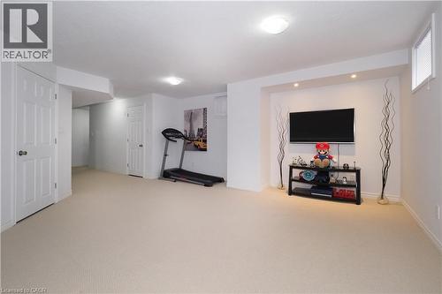 Spacious lower-level room featuring light-colored carpeting, white baseboards, and white painted walls - 213 Seabrook Drive, Kitchener, ON 