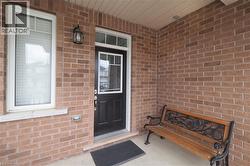 Brick exterior featuring a black entry door with decorative glass, a white-framed window with louvered blinds, and an overhead light fixture - 