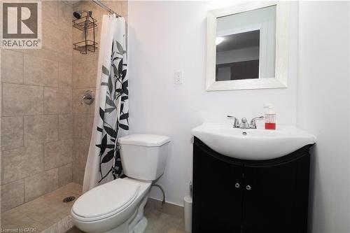 Bathroom featuring a tiled shower stall with chrome fixtures, a white toilet, and a black vanity with an integrated sink and chrome faucet - 213 Seabrook Drive, Kitchener, ON 