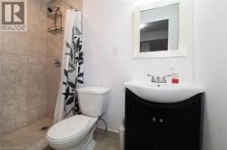 Bathroom featuring a tiled shower stall with chrome fixtures, a white toilet, and a black vanity with an integrated sink and chrome faucet - 
